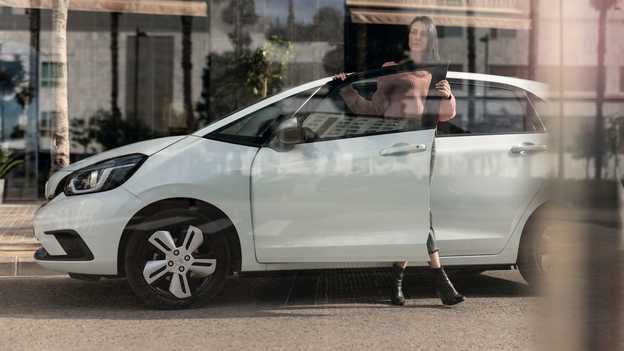 Vue latérale de la Honda Jazz garée avec une femme ouvrant la porte