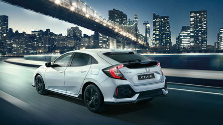 Vue de trois quarts arrière de la Honda Civic Dynamic, roulant dans un paysage urbain.