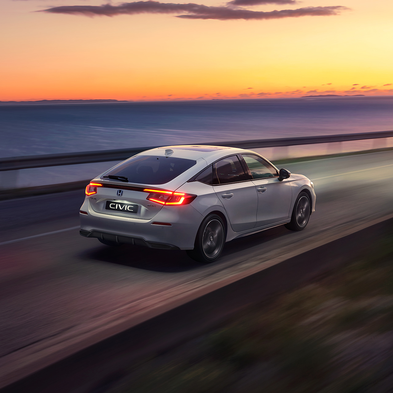 Voiture Civic Hybrid roulant au coucher du soleil.