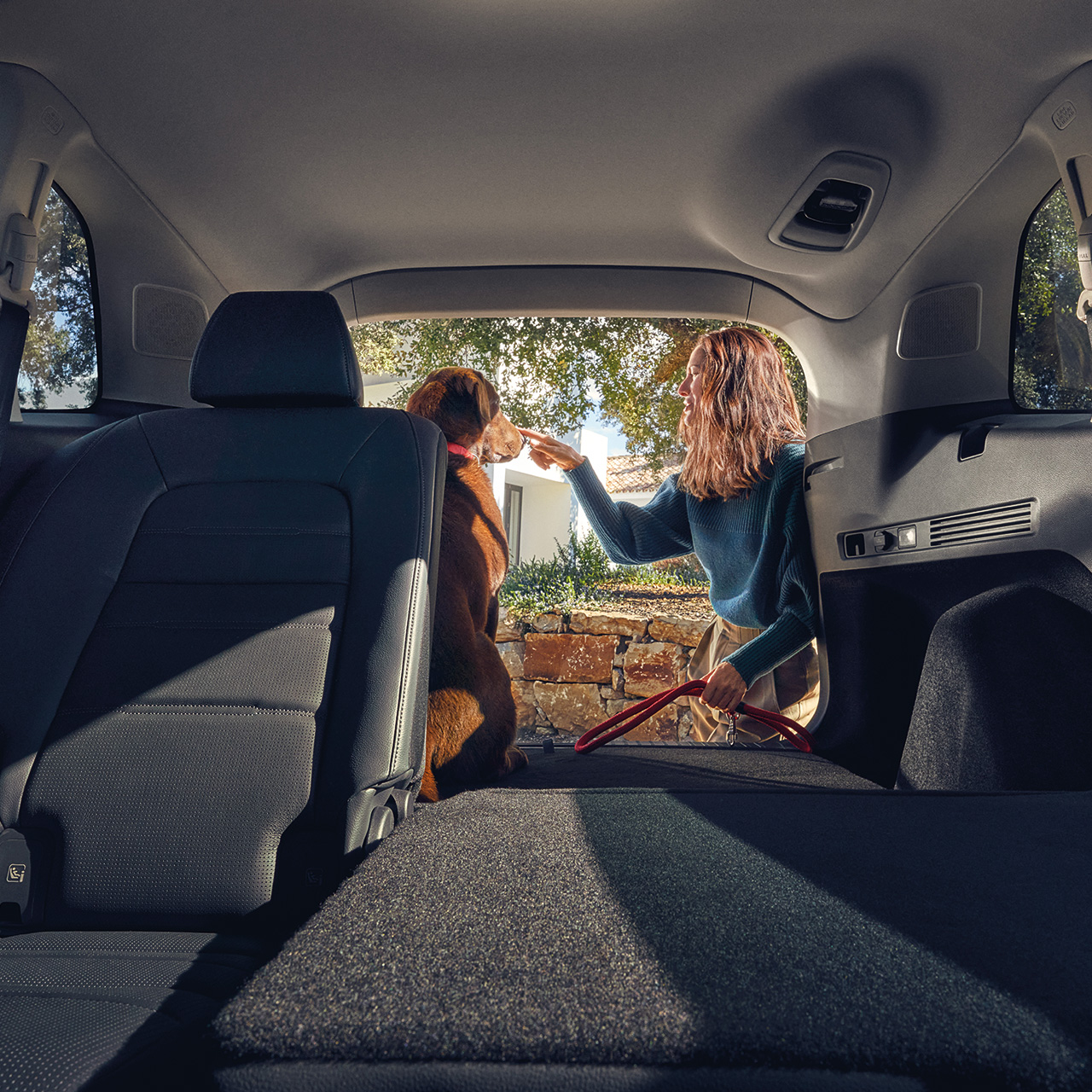 Siège arrière incliné du SUV hybride CR-V avec femme et chien dans le coffre ouvert.