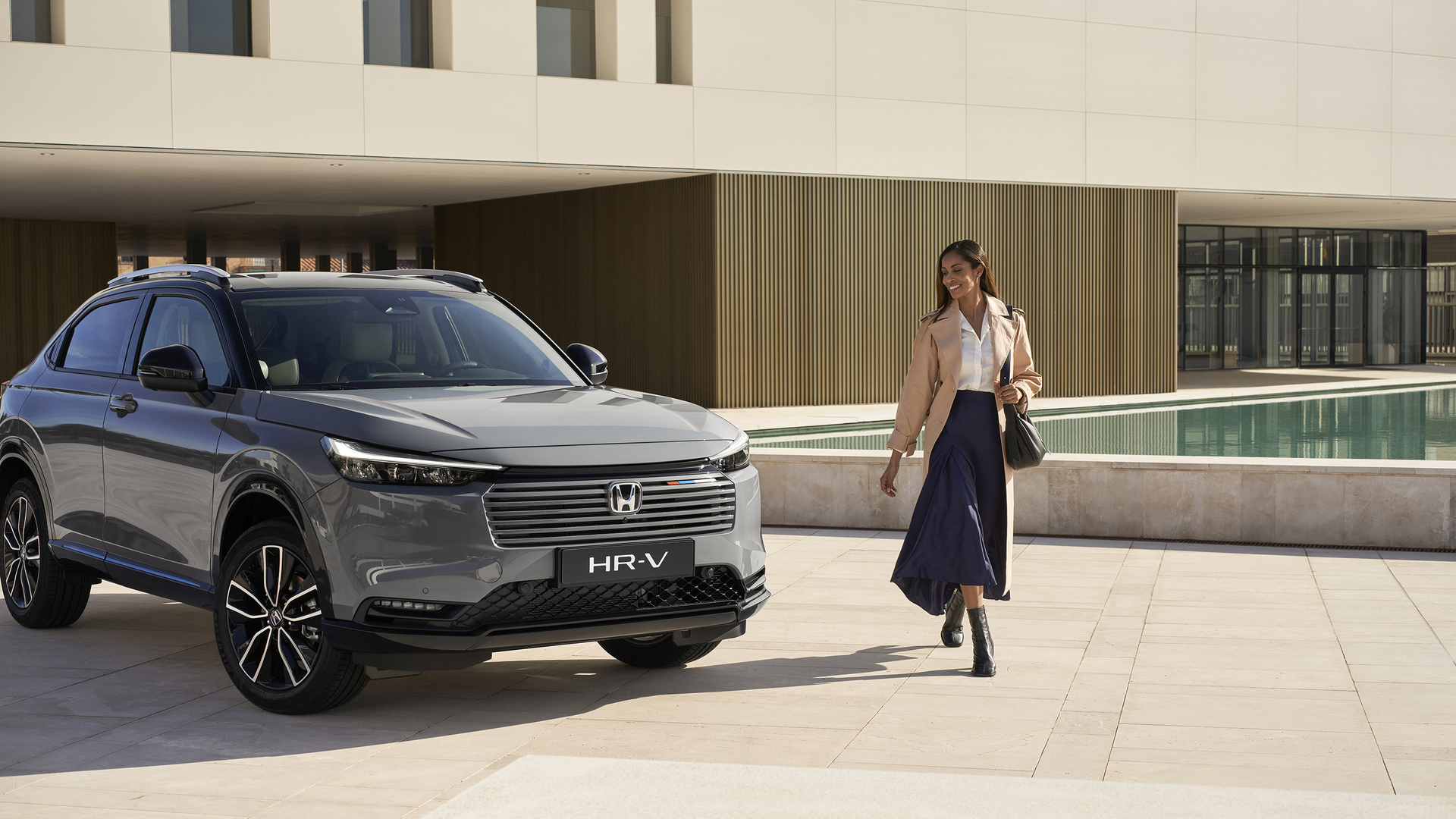 Une femme marche à côté d’un HR-V stationné à l’extérieur d’un bâtiment. 