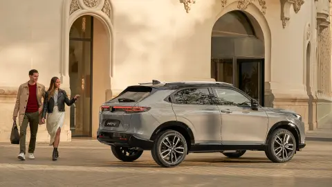 Vue latérale du Honda HR-V à l’extérieur de l’hôtel, avec un couple qui passe. 