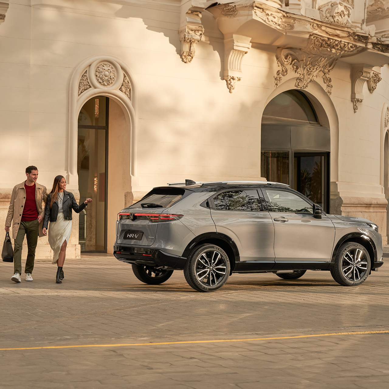 Vue latérale du Honda HR-V à l’extérieur de l’hôtel, avec un couple qui passe.